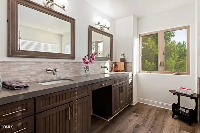 a bathroom with a granite countertop sink a large mirror a and a window