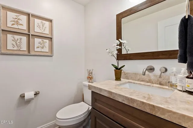 a bathroom with a granite countertop toilet sink and mirror