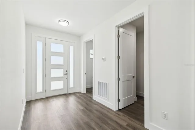 an empty room with wooden floor & windows