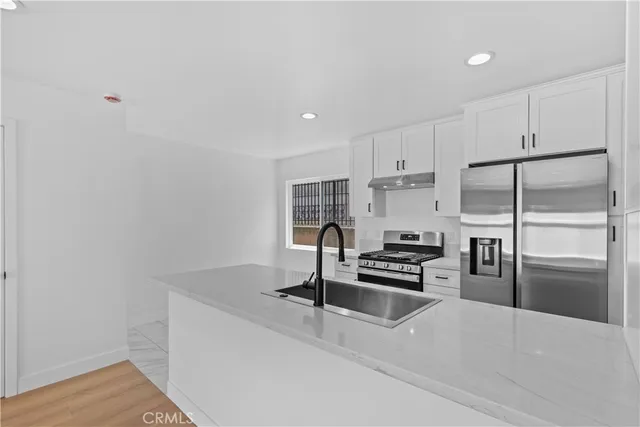 a kitchen with granite countertop a refrigerator stove and sink