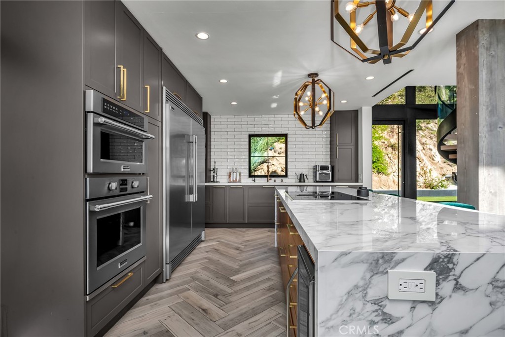 24301 Sylvan Glen Road Calabasas, CA 91302 - Photo 26 of 64 a large kitchen with stainless steel appliances granite countertop a stove a sink dishwasher and a fireplace with wooden floor
