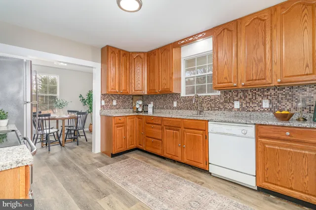 a kitchen with stainless steel appliances granite countertop wooden cabinets a sink and dishwasher a stove with wooden floor