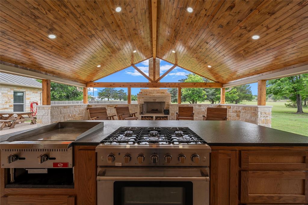 1117 Downsville Road Robinson, TX 76706 - Photo 28 of 40 Spacious outdoor kitchen area featuring a wood-plank vaulted ceiling with recessed lighting, integrated gas cooktop, and a built-in griddle