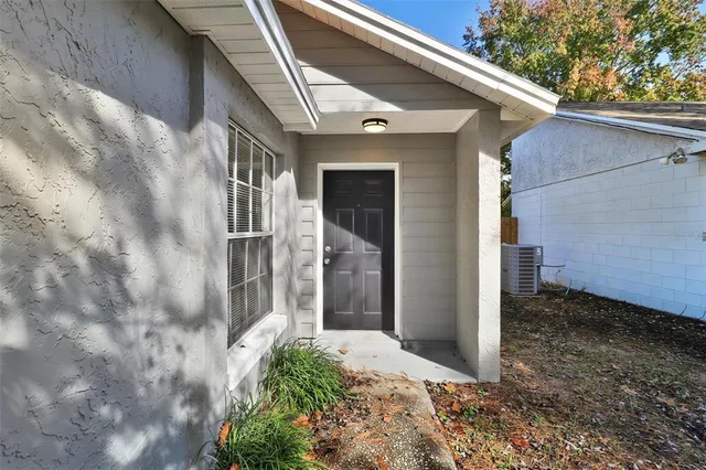 an empty room with windows and way to kitchen