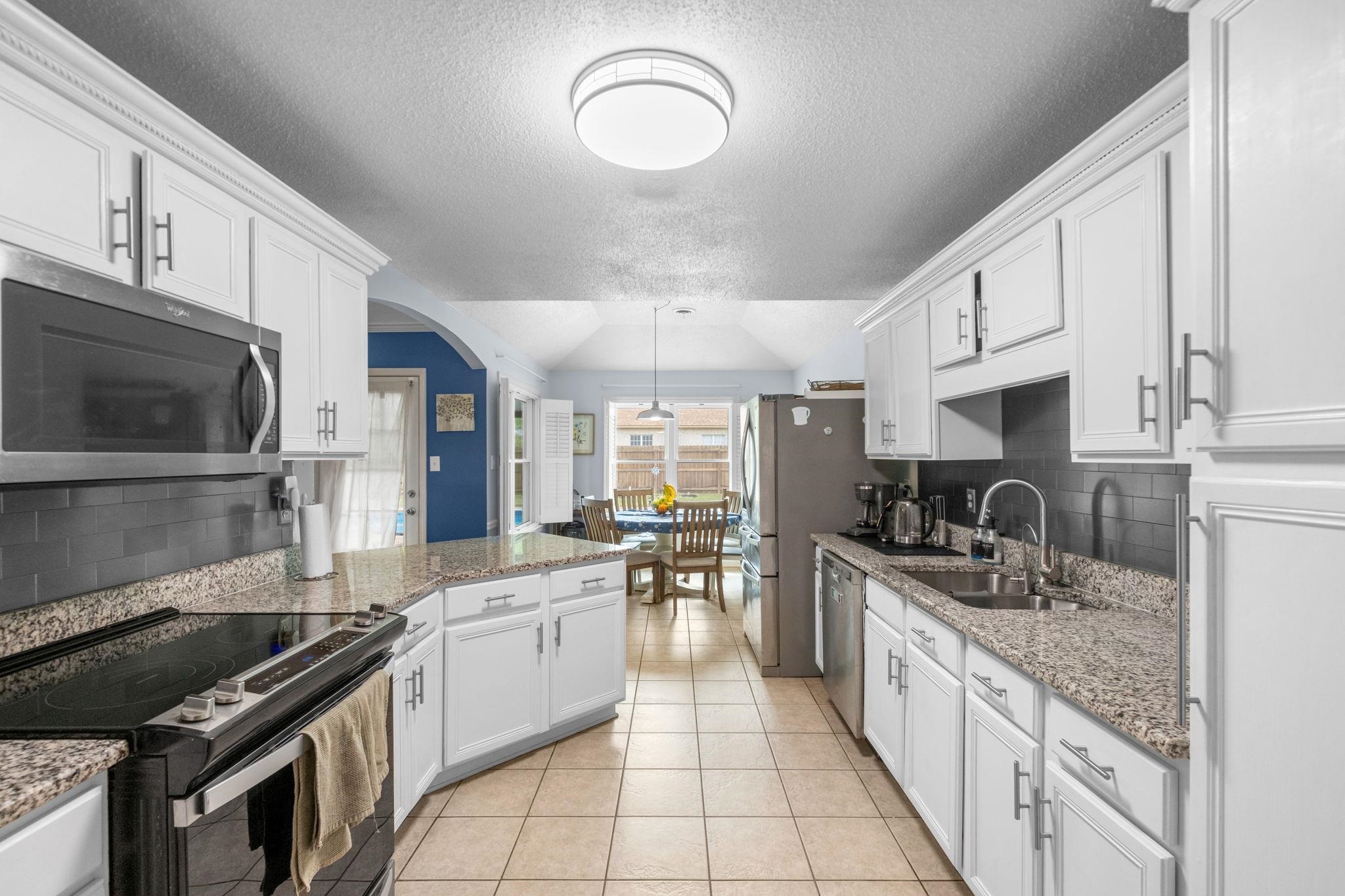 9333 Breakstone Cove Collierville, TN 38017 - Photo 14 of 39 Bright and updated kitchen featuring granite countertops, white cabinetry, stainless steel appliances, abundant prep space, and a functional layout. Perfect for everyday living and entertaining, with timeless finishes and plenty of storage throughout. ???