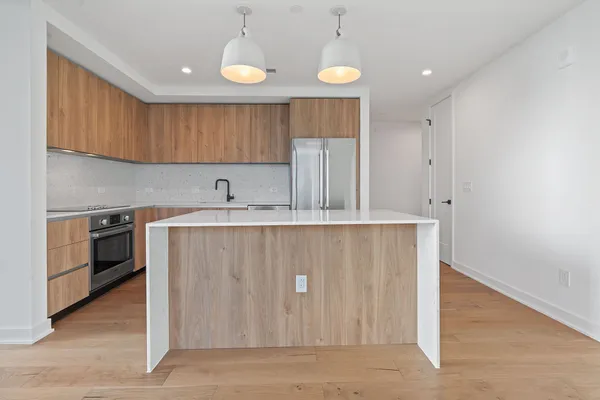 a kitchen with stainless steel appliances granite countertop a sink a refrigerator and island with wooden floor