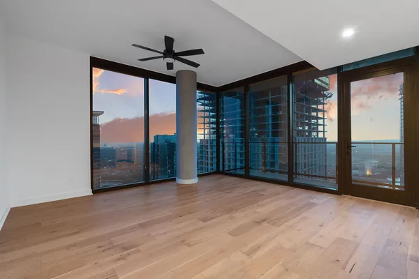 a view of empty room with wooden floor and fan