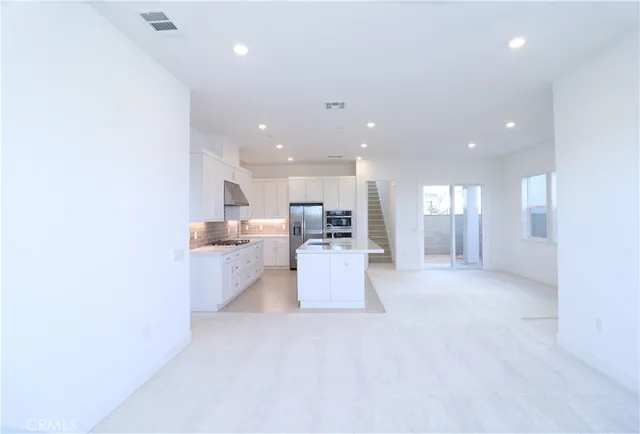 a view of a living room kitchen with stainless steel appliances cabinets