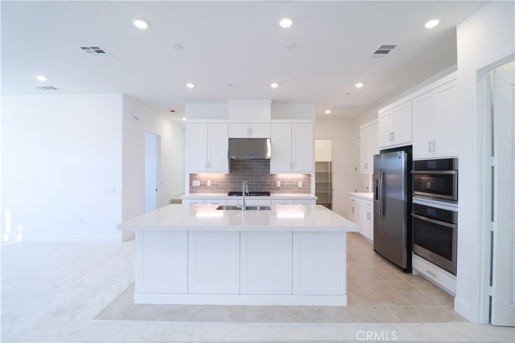 647 Gadwall Irvine, CA 92618 - Photo 6 of 29 a kitchen with stainless steel appliances kitchen island granite countertop a refrigerator and a stove top oven