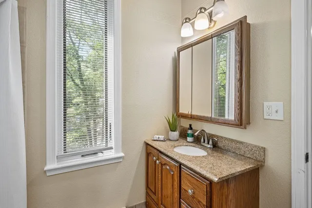 a bathroom with a granite countertop sink a mirror and a window