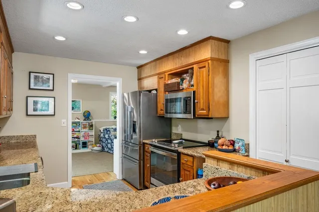 a kitchen with stainless steel appliances granite countertop a refrigerator and a stove top oven