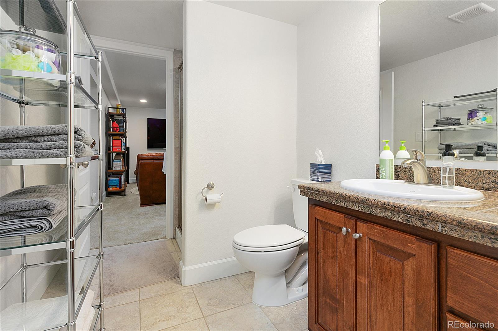 4511 Perry Street Denver, CO 80212 - Photo 23 of 36 a bathroom with a granite countertop sink a toilet and a shower