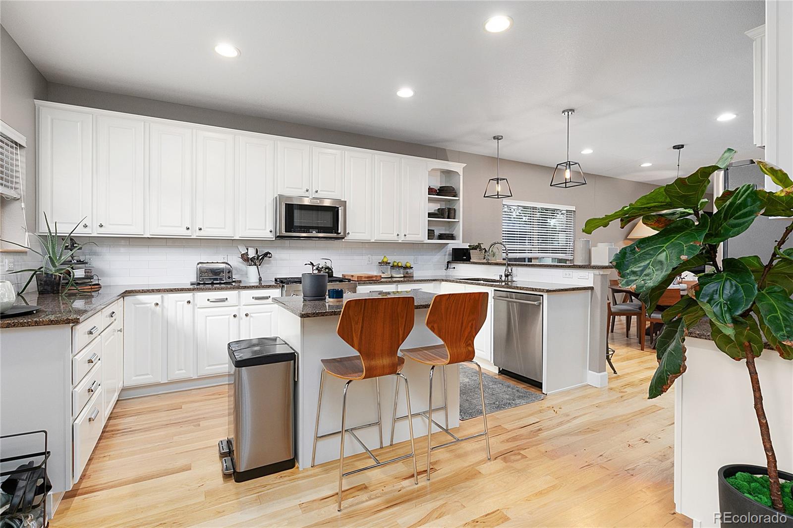 4511 Perry Street Denver, CO 80212 - Photo 9 of 36 a kitchen with stainless steel appliances kitchen island granite countertop a stove a sink a refrigerator and a white cabinets