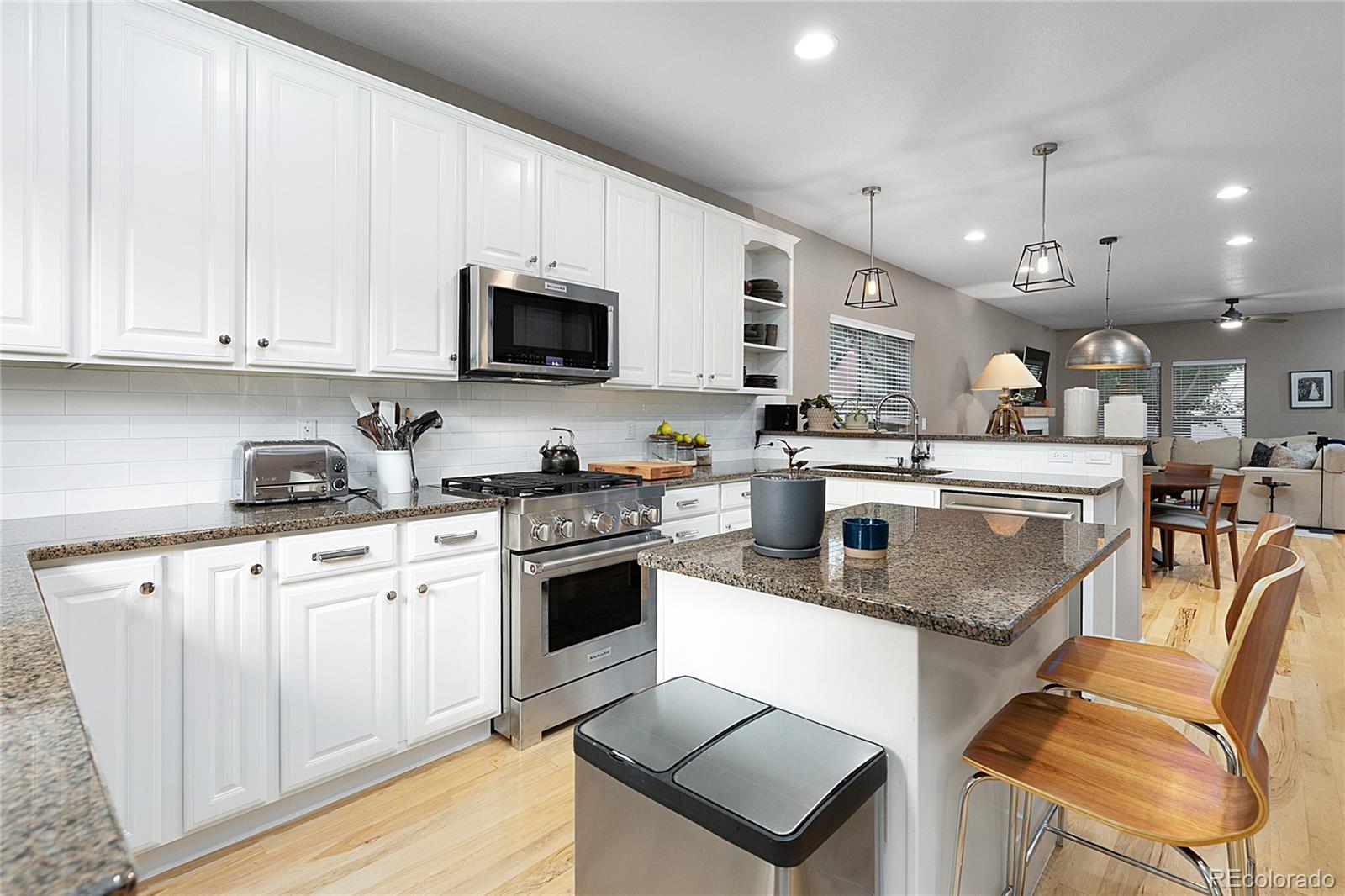 4511 Perry Street Denver, CO 80212 - Photo 10 of 36 a kitchen with stainless steel appliances granite countertop a stove top oven a sink dishwasher and white cabinets with wooden floor