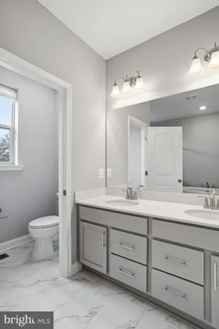 a bathroom with a toilet sink double vanity and mirror