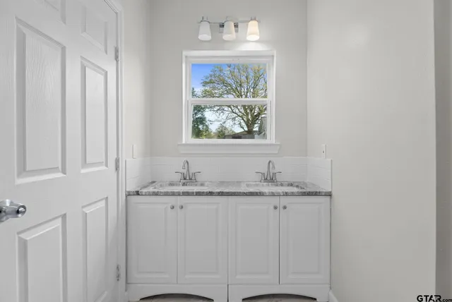 a bathroom with a granite countertop sink and a window