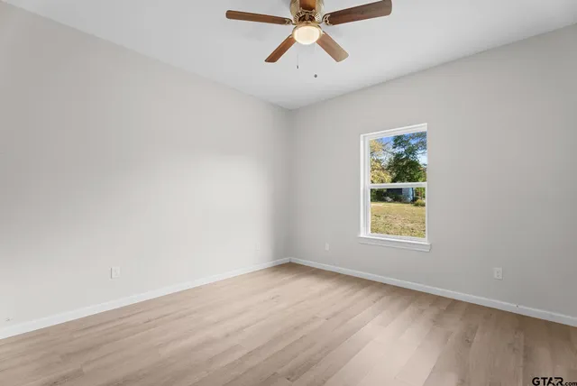 an empty room with a window and a fan