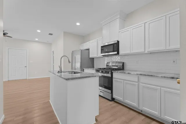 a kitchen with stainless steel appliances granite countertop a sink stove and microwave