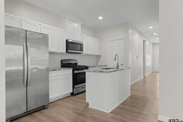 a kitchen with a refrigerator a microwave a sink and cabinets