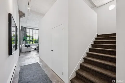a view of a hallway to a livingroom with wooden floor and stairs