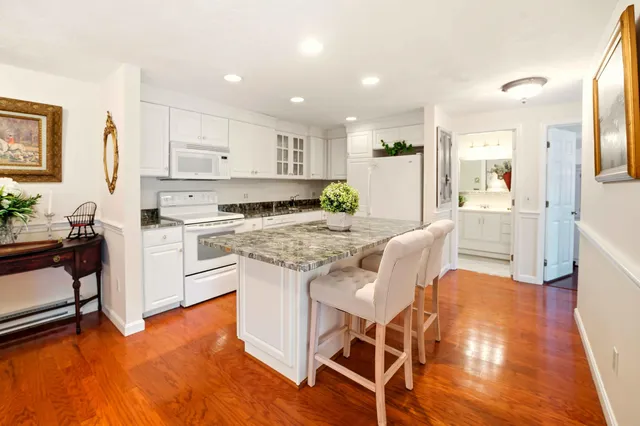 a kitchen with a sink a stove a refrigerator and white cabinets with wooden floor