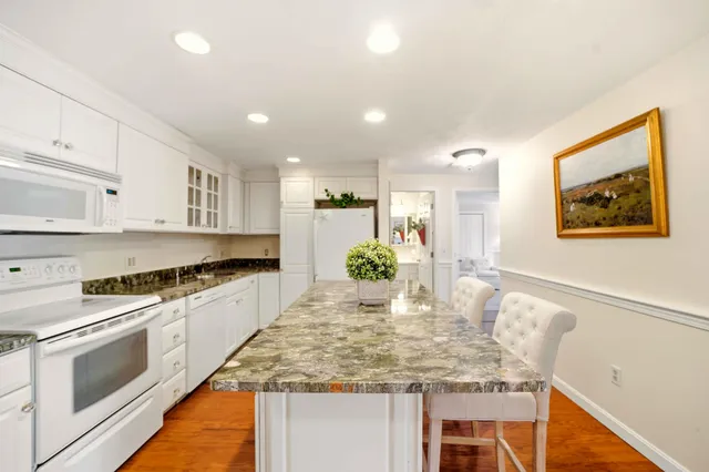 a kitchen with kitchen island granite countertop wooden cabinets and white appliances