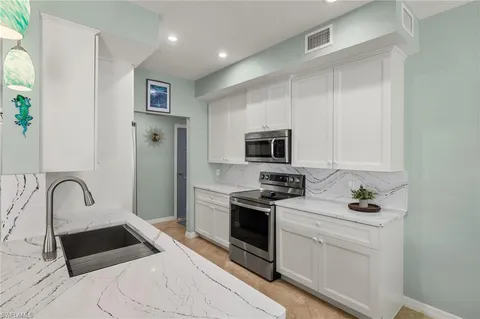 a kitchen with stainless steel appliances granite countertop a stove a sink and a microwave