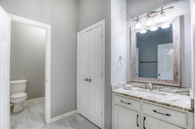a bathroom with a granite countertop sink a toilet and a mirror