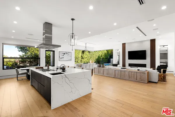 a view of living room kitchen with stainless steel appliances granite countertop a stove and a couch