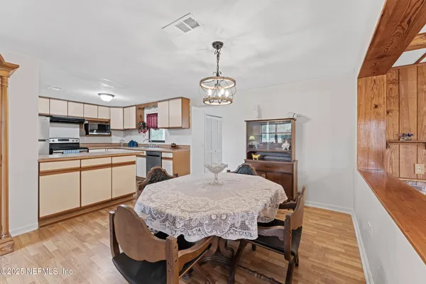a kitchen with kitchen island a dining table chairs stainless steel appliances and cabinets