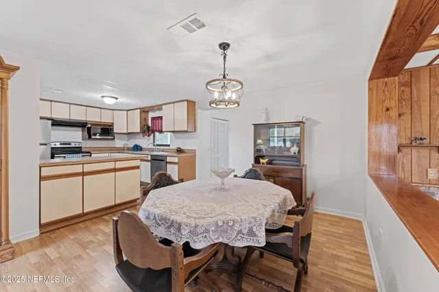 a kitchen with kitchen island a dining table chairs stainless steel appliances and cabinets