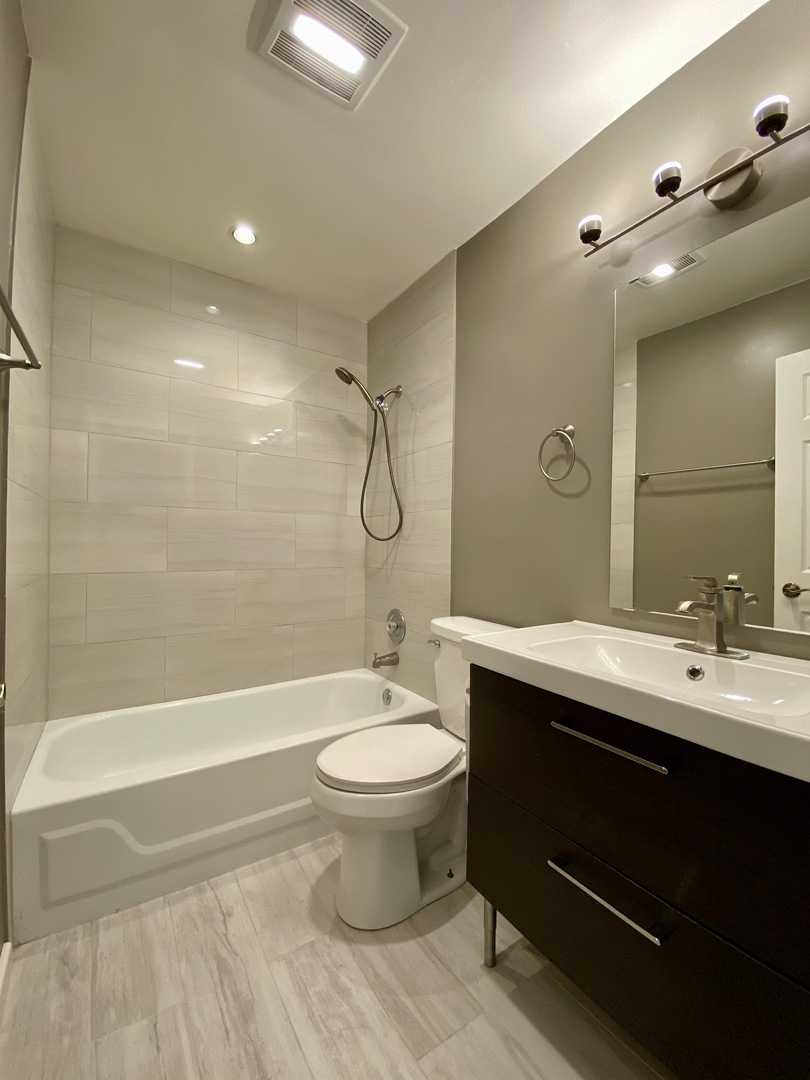 1115 Scanlon Drive, Unit B1 Wheeling, IL 60090 - Photo 10 of 12 a bathroom with a double vanity sink toilet mirror and shower