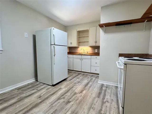 a kitchen with granite countertop white cabinets and refrigerator