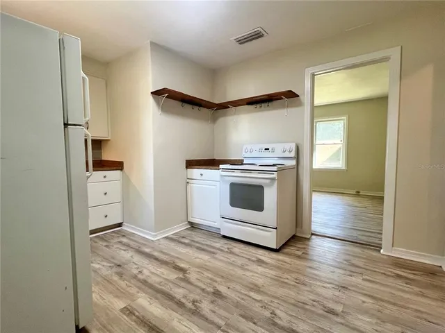 a kitchen with stainless steel appliances wooden floor and a sink
