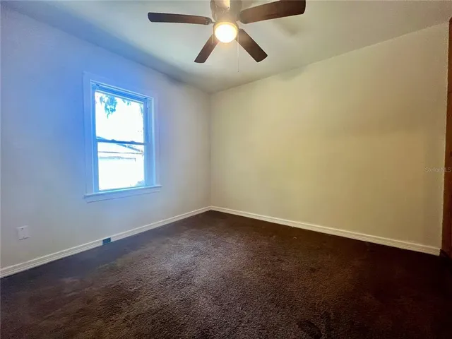 an empty room with a window and a fan