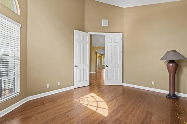 an empty room with wooden floor and windows