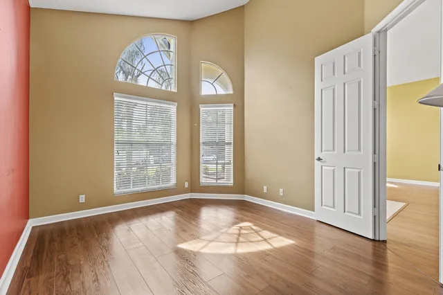 an empty room with wooden floor and windows
