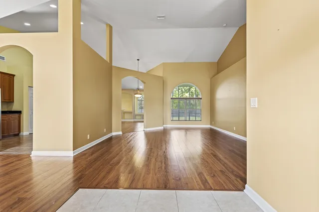 a view of an empty room with window and wooden floor