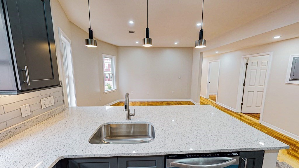 109 Deering Road, Unit 1 Boston, MA 02126 - Photo 4 of 12 a kitchen with stainless steel appliances a sink dishwasher a refrigerator with white cabinets and wooden floor