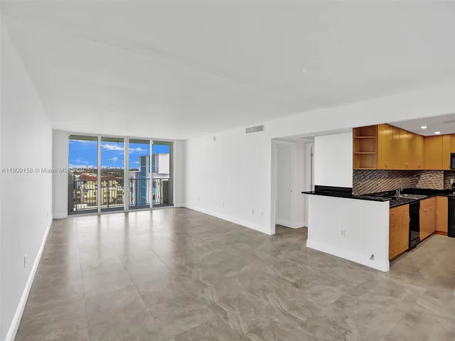 a living room with stainless steel appliances kitchen island granite countertop a stove and a refrigerator