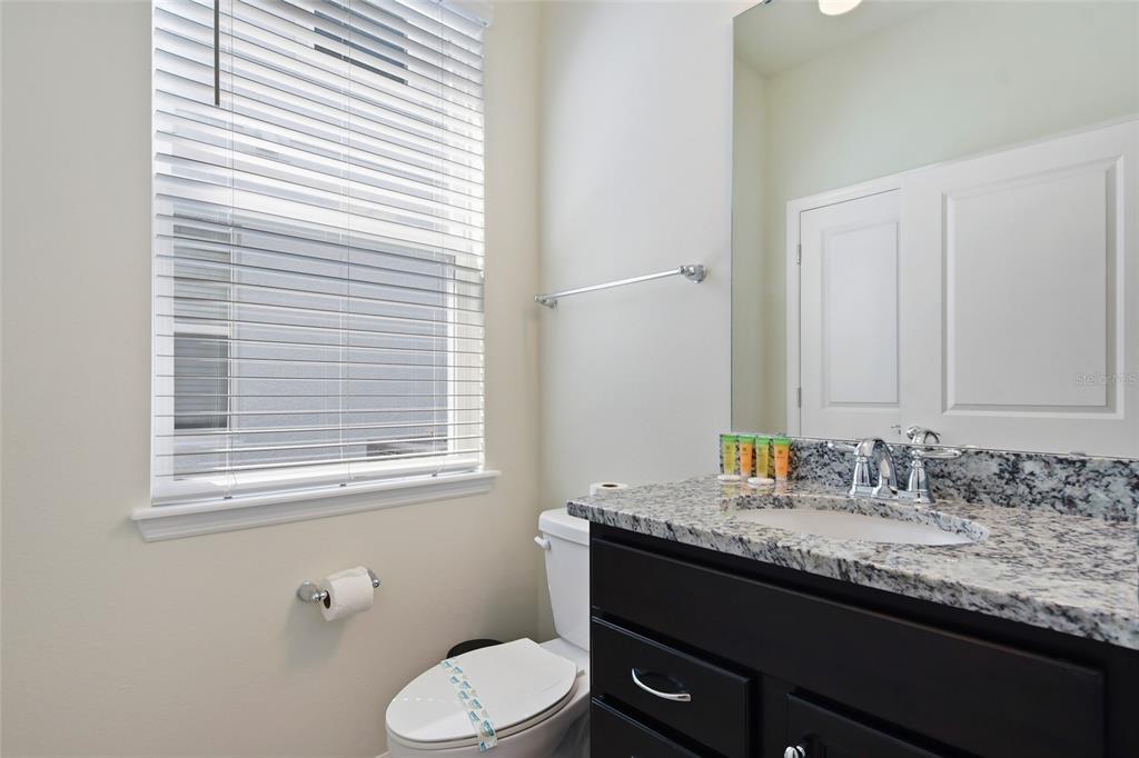 4428 Kaipo Road Davenport, FL 33897 - Photo 18 of 73 a bathroom with a granite countertop sink toilet and mirror