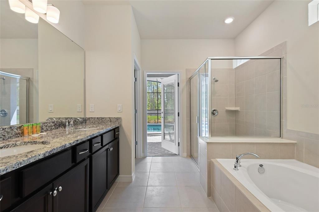 4428 Kaipo Road Davenport, FL 33897 - Photo 22 of 73 a spacious bathroom with a granite countertop tub sink shower and mirror