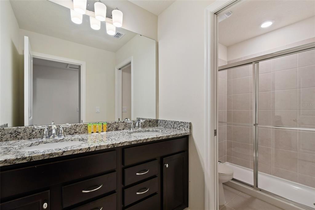 4428 Kaipo Road Davenport, FL 33897 - Photo 36 of 73 a bathroom with a granite countertop sink a mirror and a shower