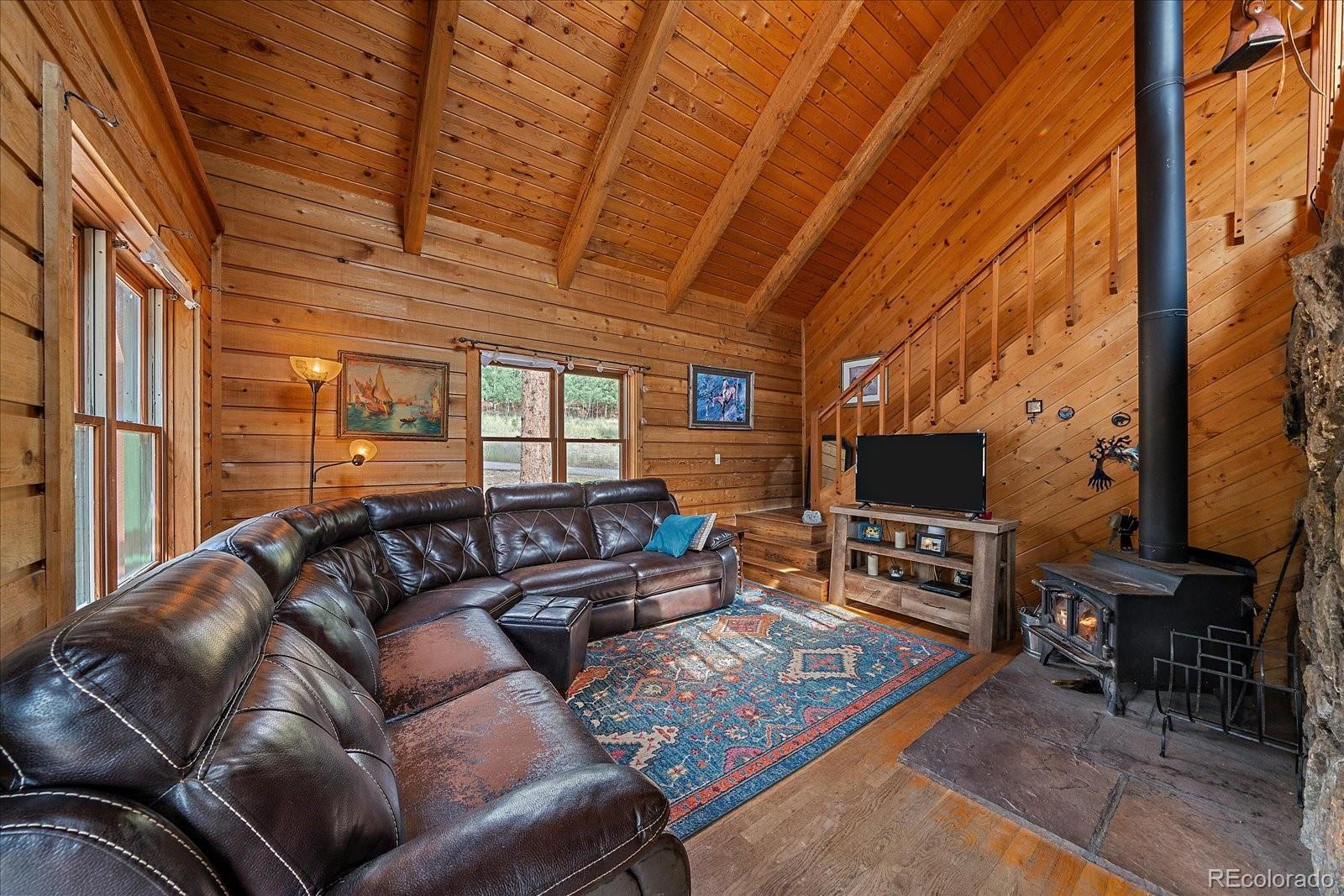 104 Six Bits Street Bailey, CO 80421 - Photo 9 of 46 a living room with furniture a flat screen tv and a floor to ceiling window