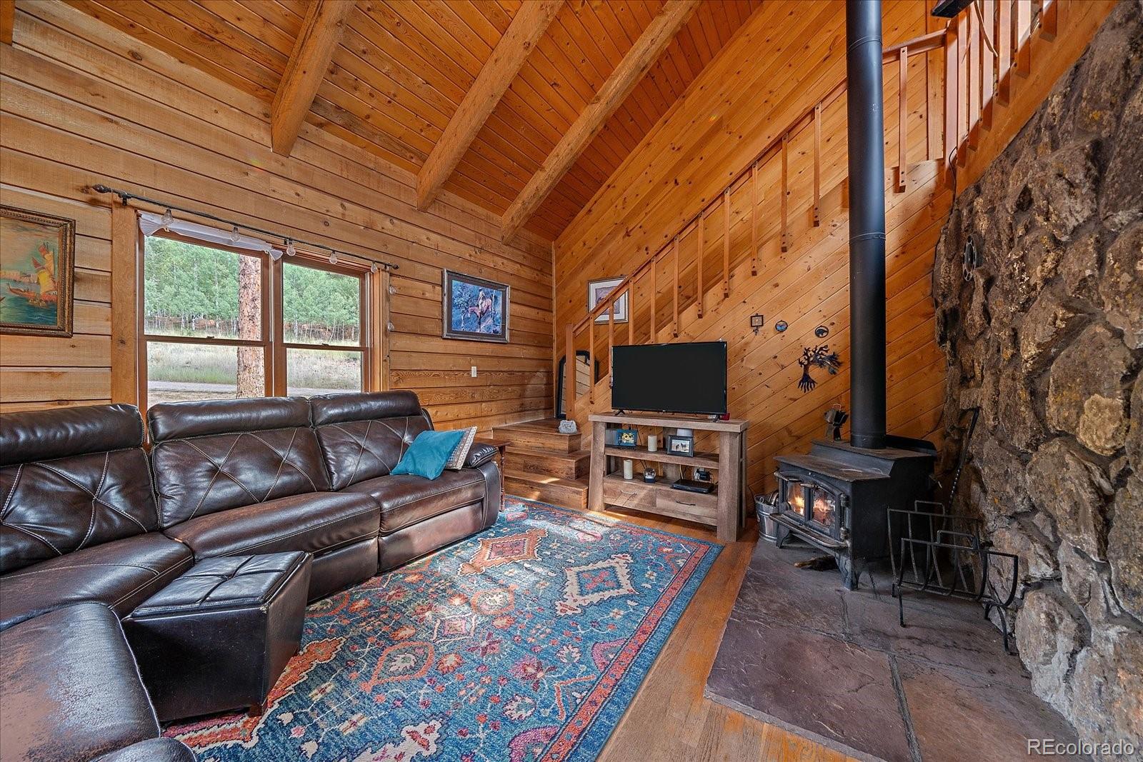 104 Six Bits Street Bailey, CO 80421 - Photo 10 of 46 a living room with furniture a flat screen tv and a floor to ceiling window