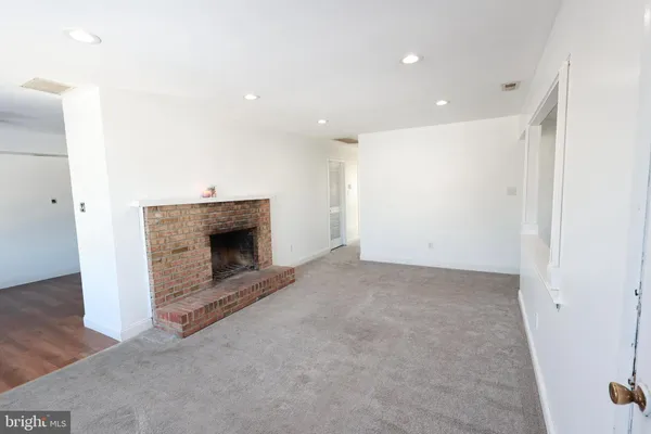 an empty room with a fireplace and kitchen view