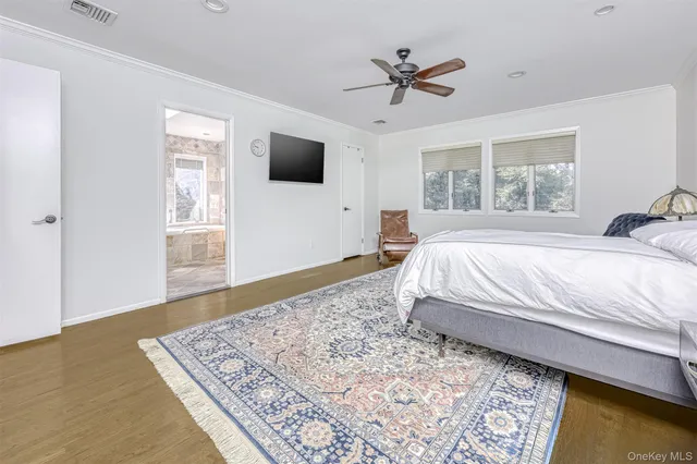 a spacious bedroom with a bed a flat screen tv and a window