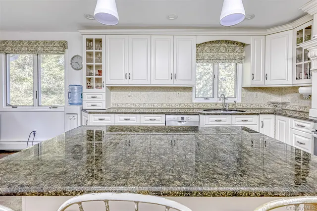 a kitchen with stainless steel appliances granite countertop a stove a sink and a granite counter tops with white cabinets
