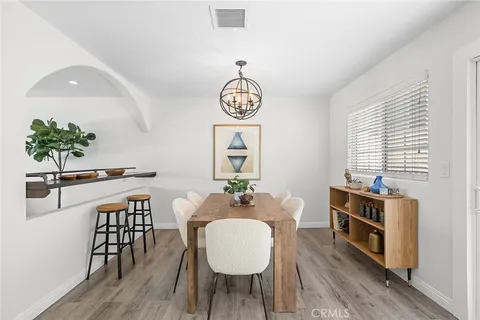 a dining room with wooden floor a chandelier a wooden table and chairs