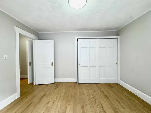 a view of an empty room with wooden floor and closet